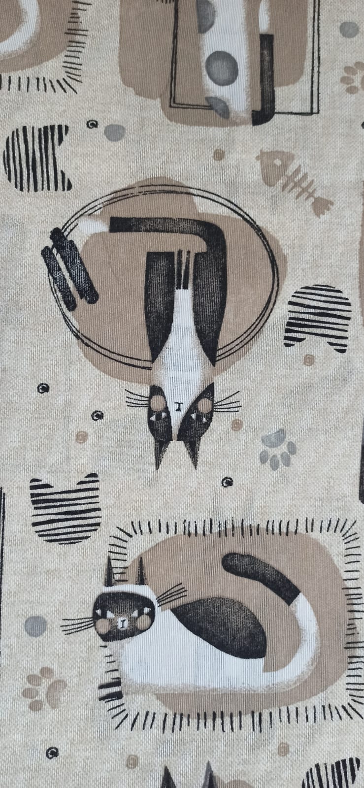 Estampado de la loneta Gatuna con un gato estirado dentro de un círculo y otro tumbado sobre un cojín beige