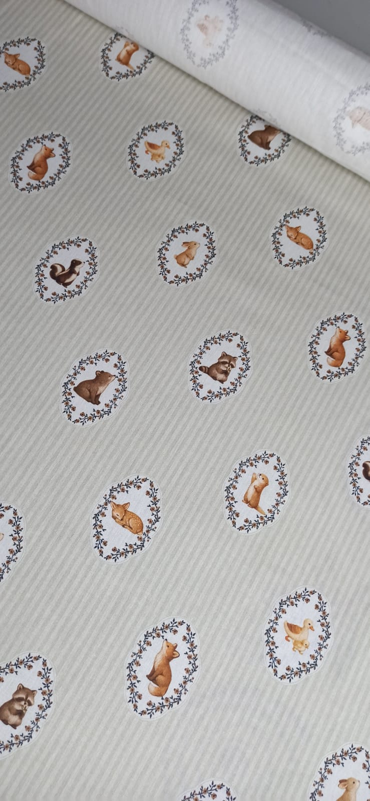 Estampado infantil de animales enmarcados con guirnaldas vegetales en tela de algodón