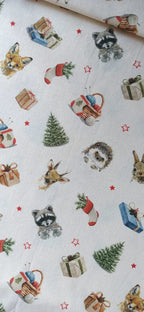 Estampado de mapaches, zorros, conejos y erizos con regalos, calcetines y estrellas rojas sobre fondo claro.