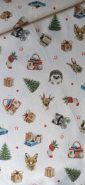 Tela de algodón sobre fondo claro con animales del bosque, regalos, abetos y estrellas rojas de Navidad.