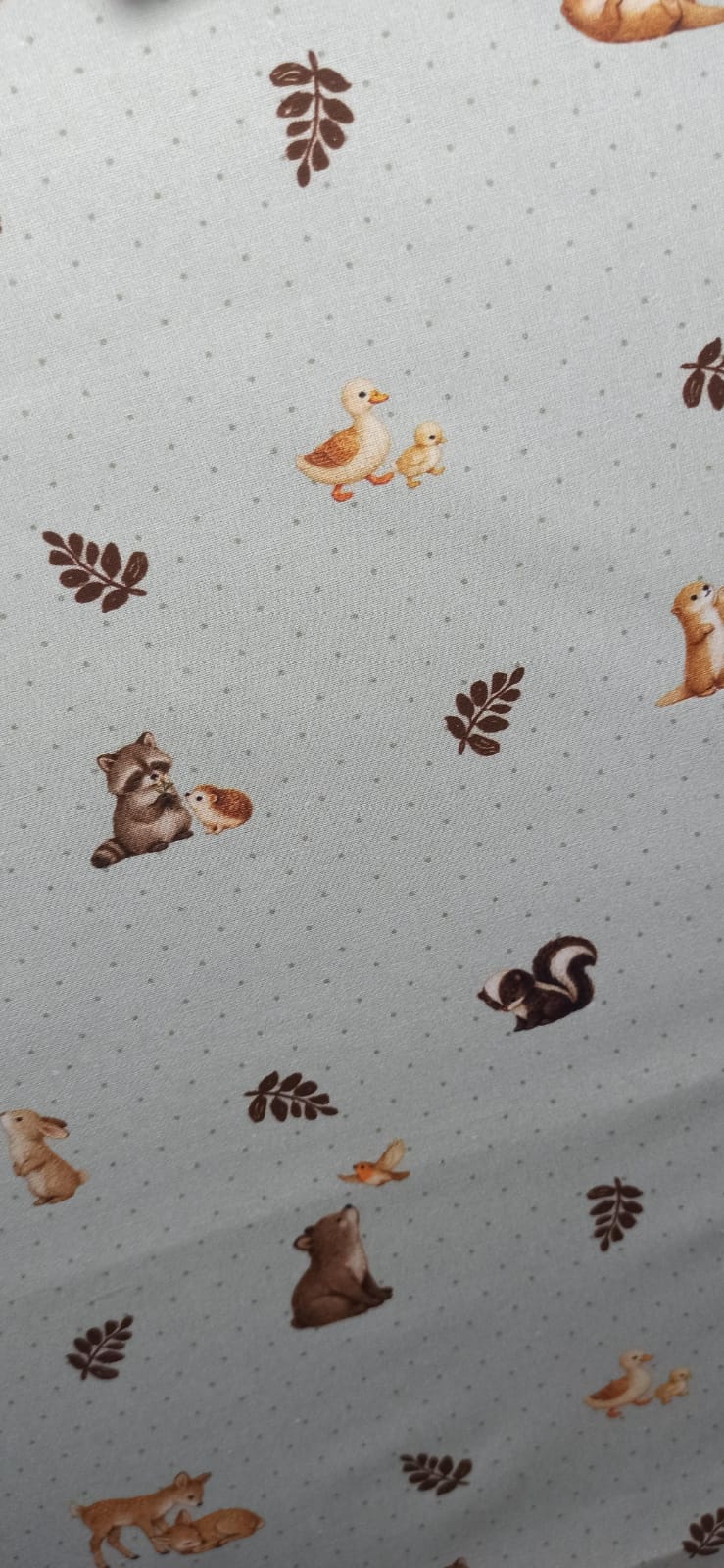 Estampado de animalitos en tonos naturales y hojas sobre algodón claro con puntitos