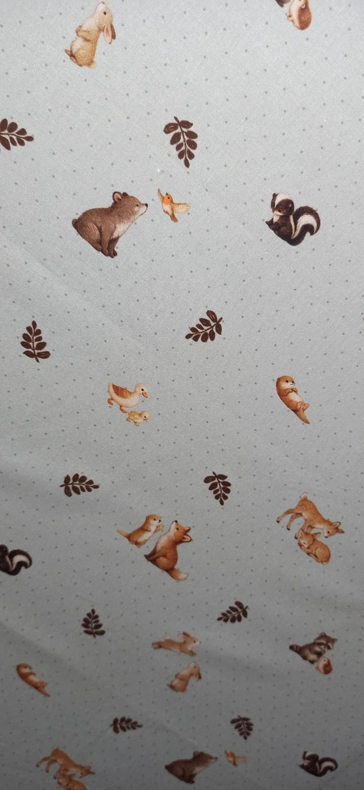 Tela de algodón con animales y motivos vegetales sobre fondo claro de pequeños puntos