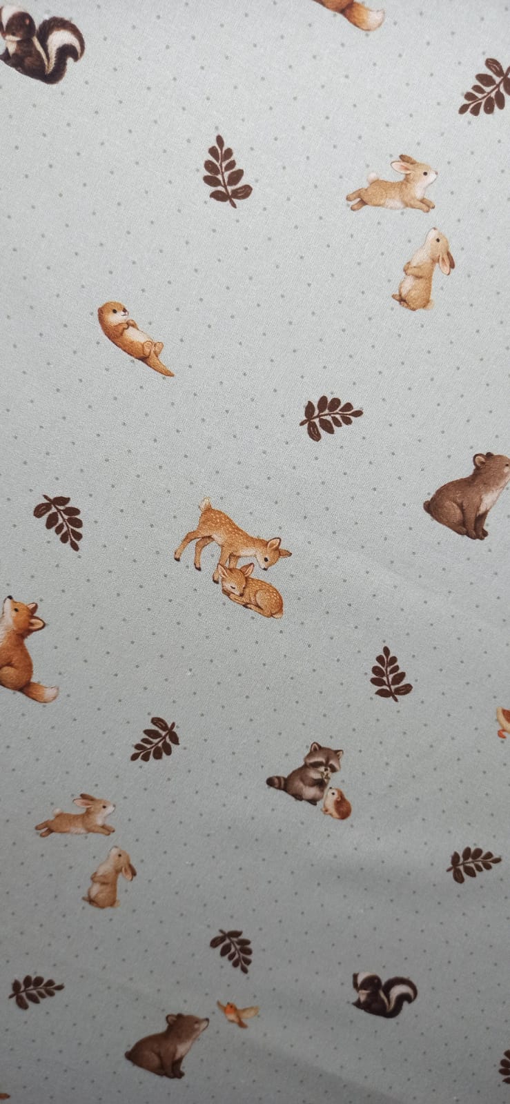 Tela de algodón con animalitos y hojas marrones sobre fondo claro de puntitos