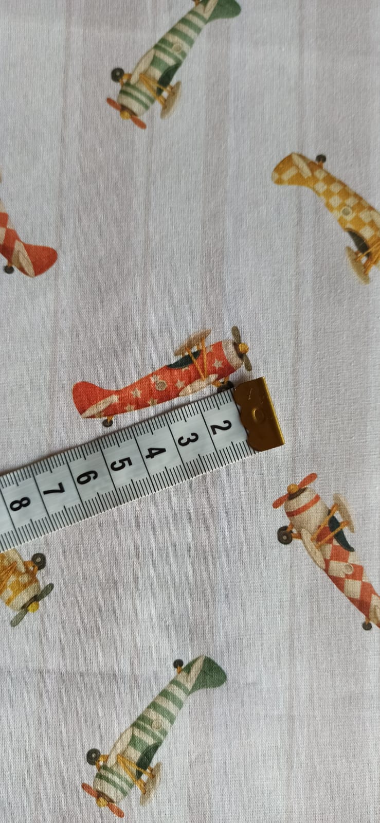 Tela de algodón con aviones vintage rojos, verdes y mostaza sobre fondo de rayas beige