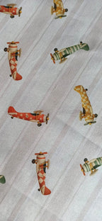 Tela de algodón con aviones vintage rojos, verdes y mostaza sobre fondo de rayas beige