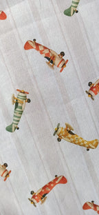 Tela de algodón con aviones vintage rojos, verdes y mostaza sobre fondo de rayas beige