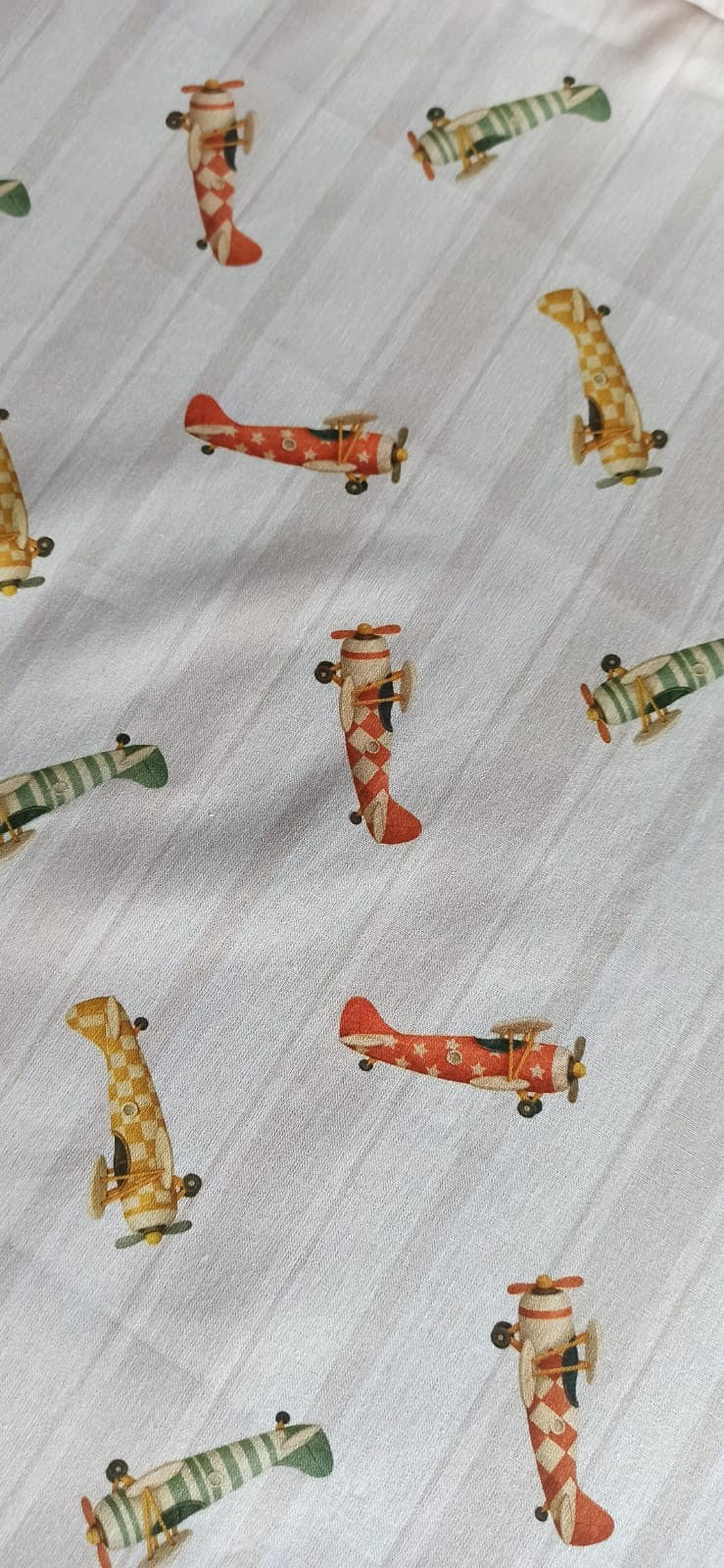 Tela de algodón con aviones vintage rojos, verdes y mostaza sobre fondo de rayas beige