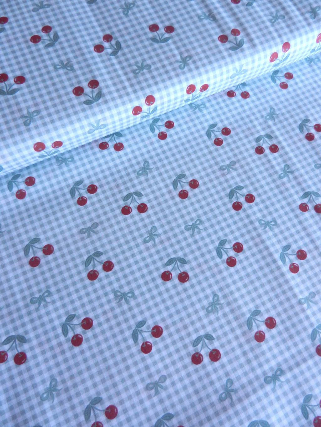 Tela de cerezas rojas sobre cuadros vichy verde