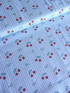 Tela de cerezas rojas sobre cuadros vichy verde