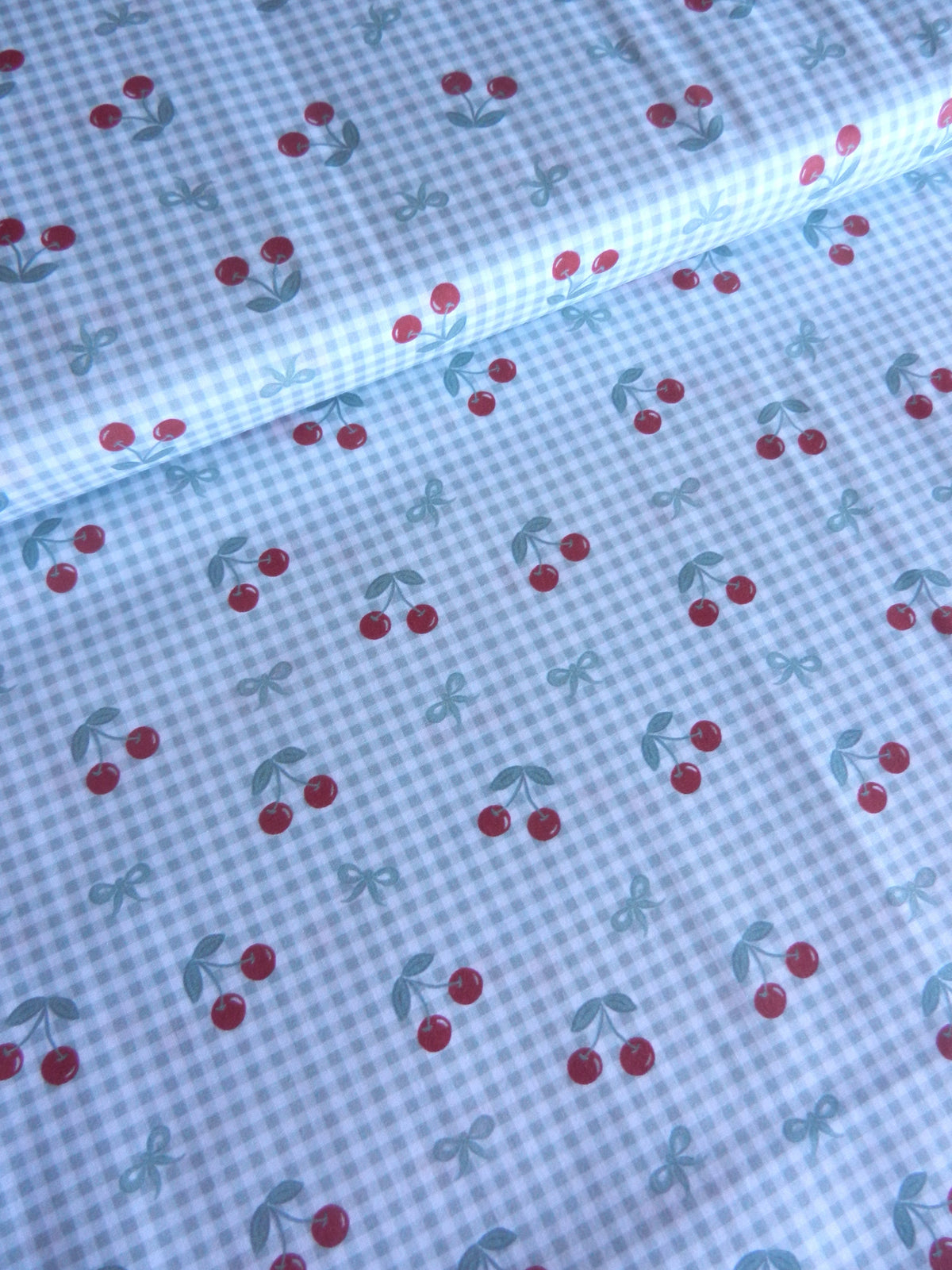 Tela de cerezas rojas sobre cuadros vichy verde