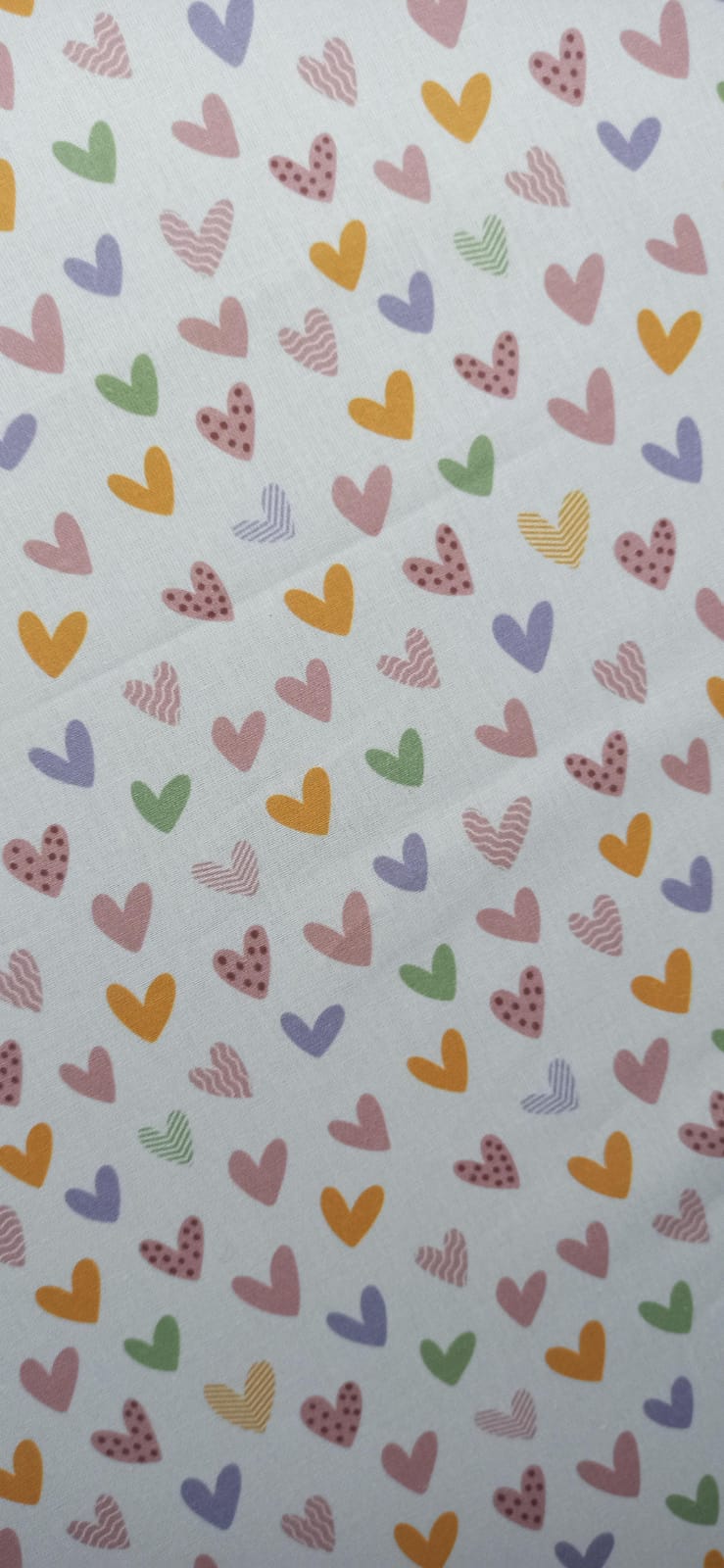 Algodón con pequeños corazones multicolor repartidos sobre fondo claro