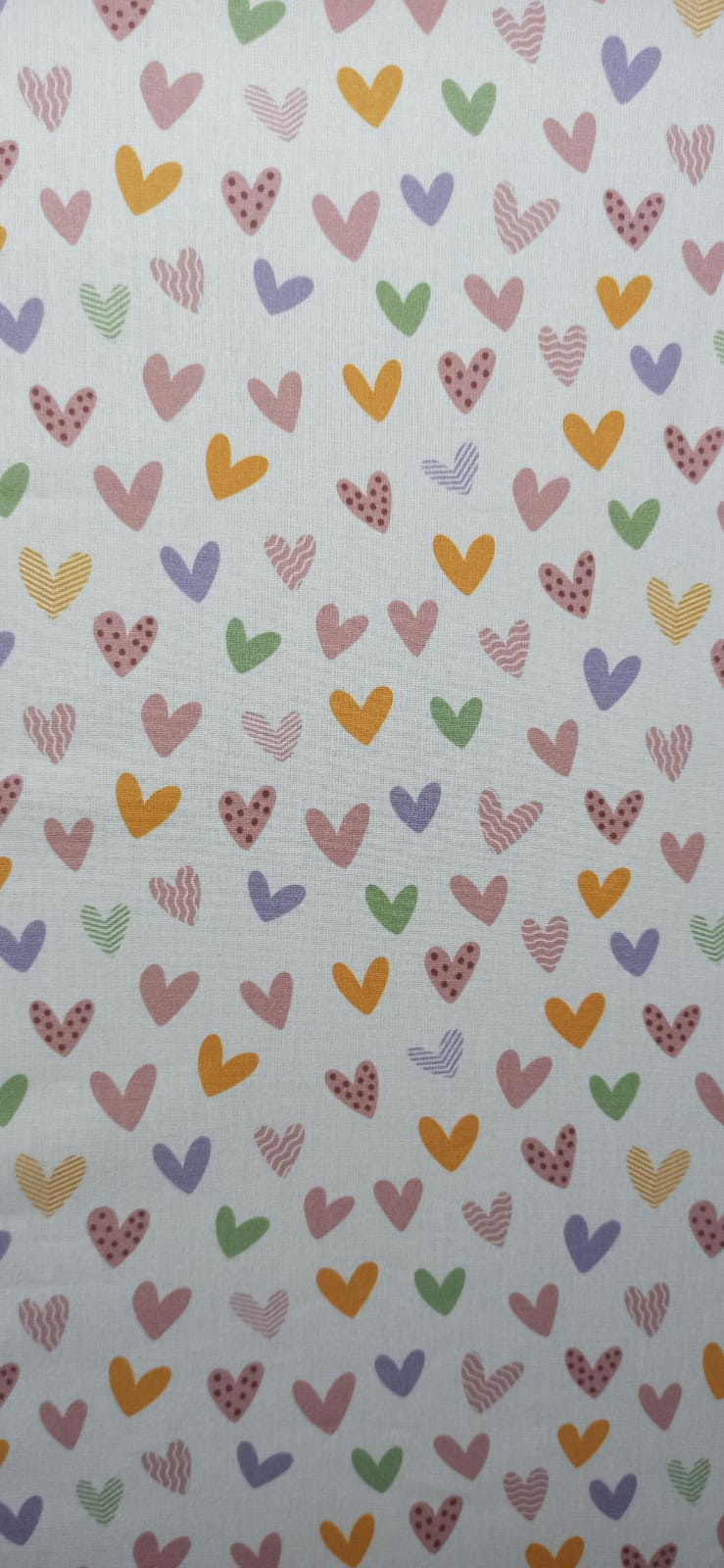 Detalle de corazones rosas, verdes, lilas y mostaza en tela de algodón