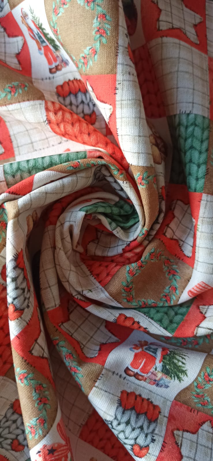 Retal de algodón de cuadros navideños dispuesto en pliegues, en rojo, verde, blanco y beige.