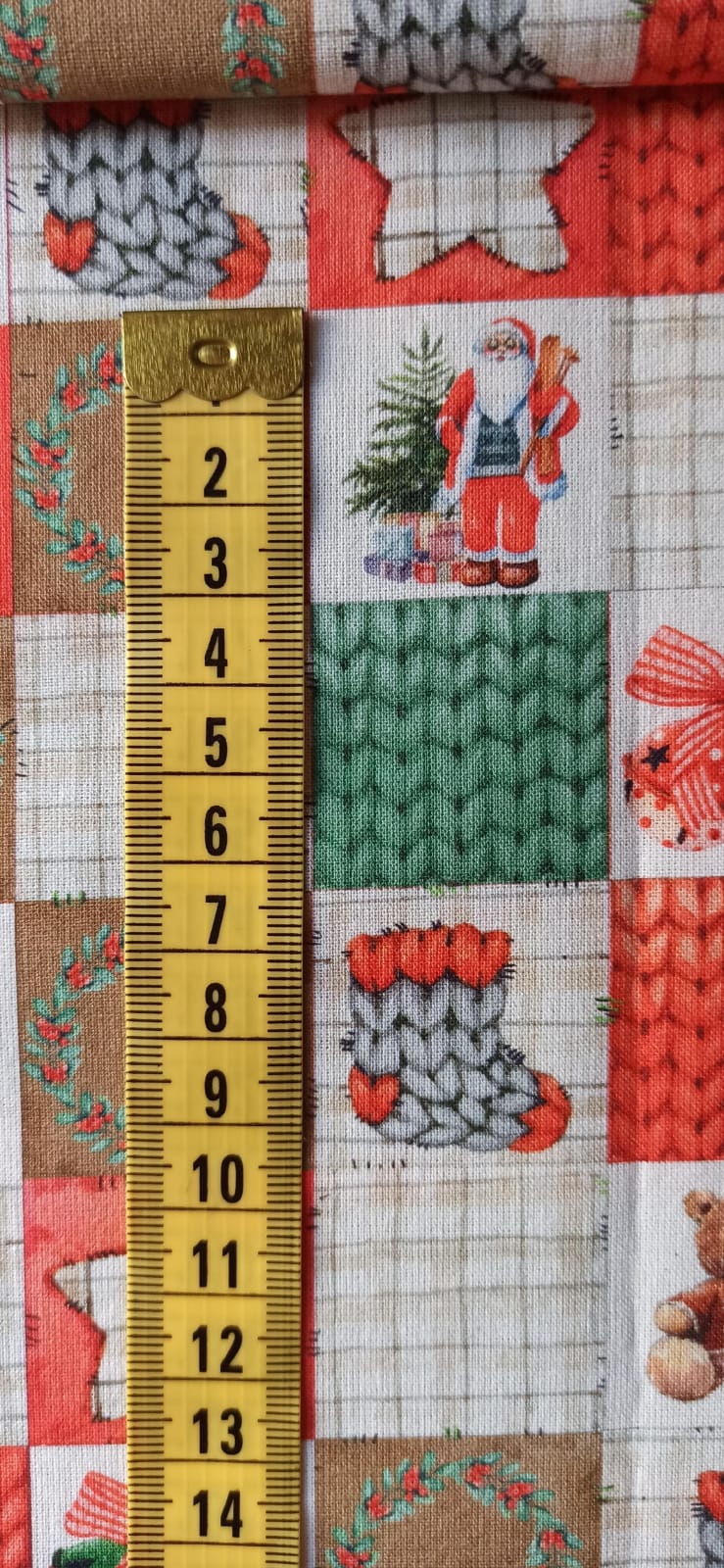 Detalle del estampado de cuadros navideños junto a una cinta métrica para apreciar el tamaño de los motivos.