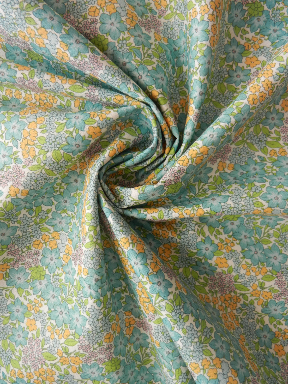 Vista general del estampado floral aguamarina, amarillo y lila con hojas verdes