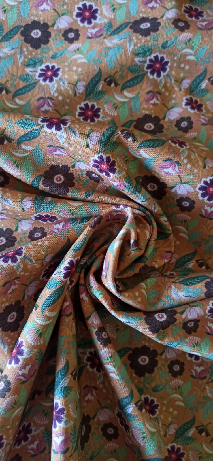 Tela de algodón estampado con flores moradas, rosas y blancas sobre fondo mostaza