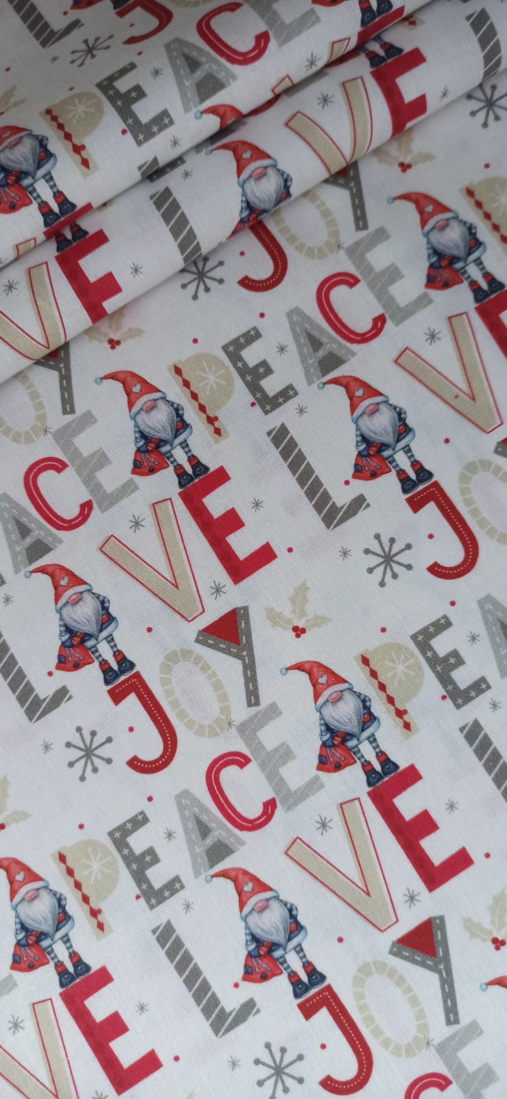 Detalle del estampado navideño de gnomos y letras en rojo, gris y beige