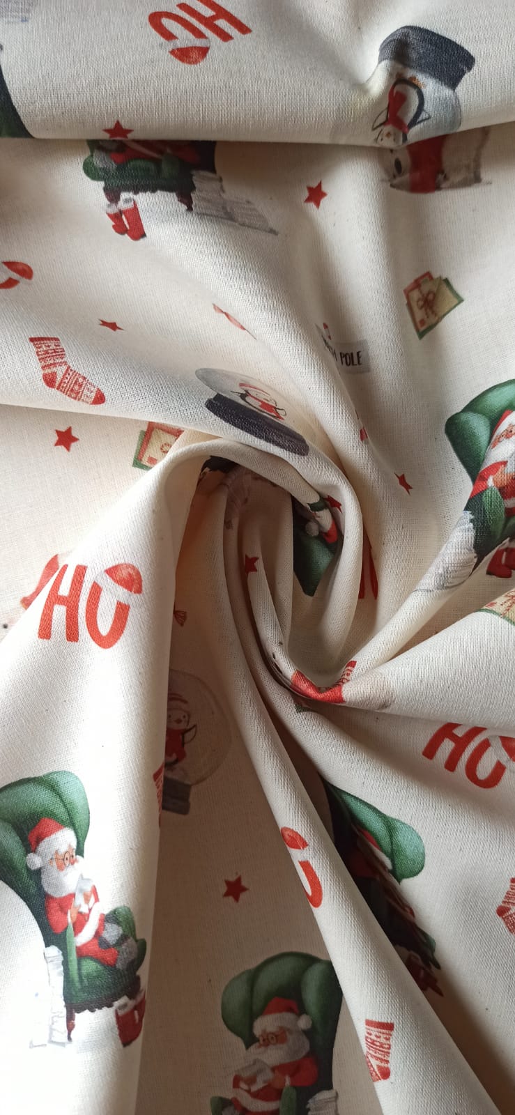 Retal navideño de algodón dispuesto en espiral con Papá Noel en sillón verde sobre fondo crema.
