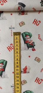 Detalle de Papá Noel en sillón verde junto a una cinta métrica para apreciar el tamaño del estampado.