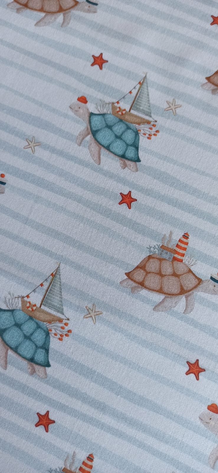 Tela de tortugas marinas sobre fondo de rayas azules