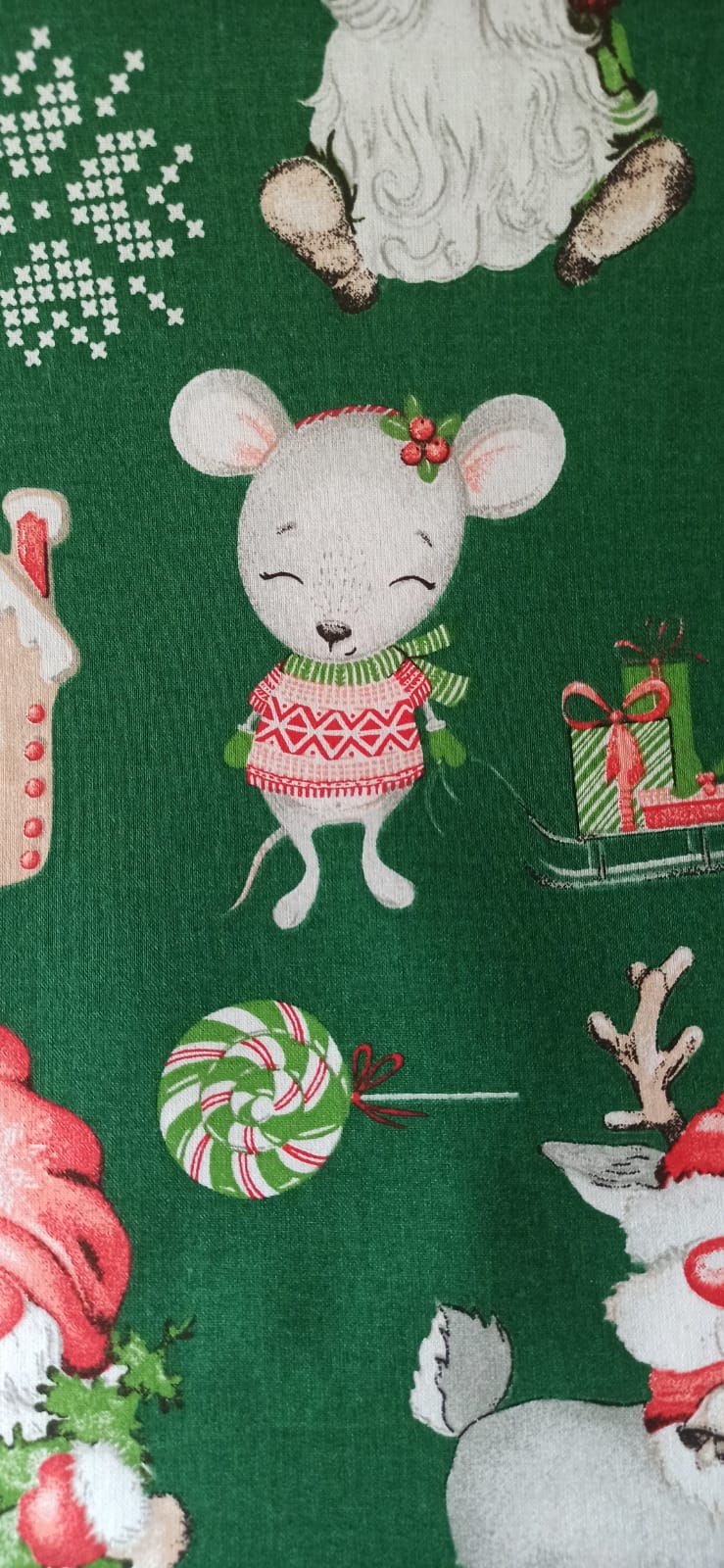Detalle de ratoncita con jersey rojo, piruleta y regalos sobre tela verde