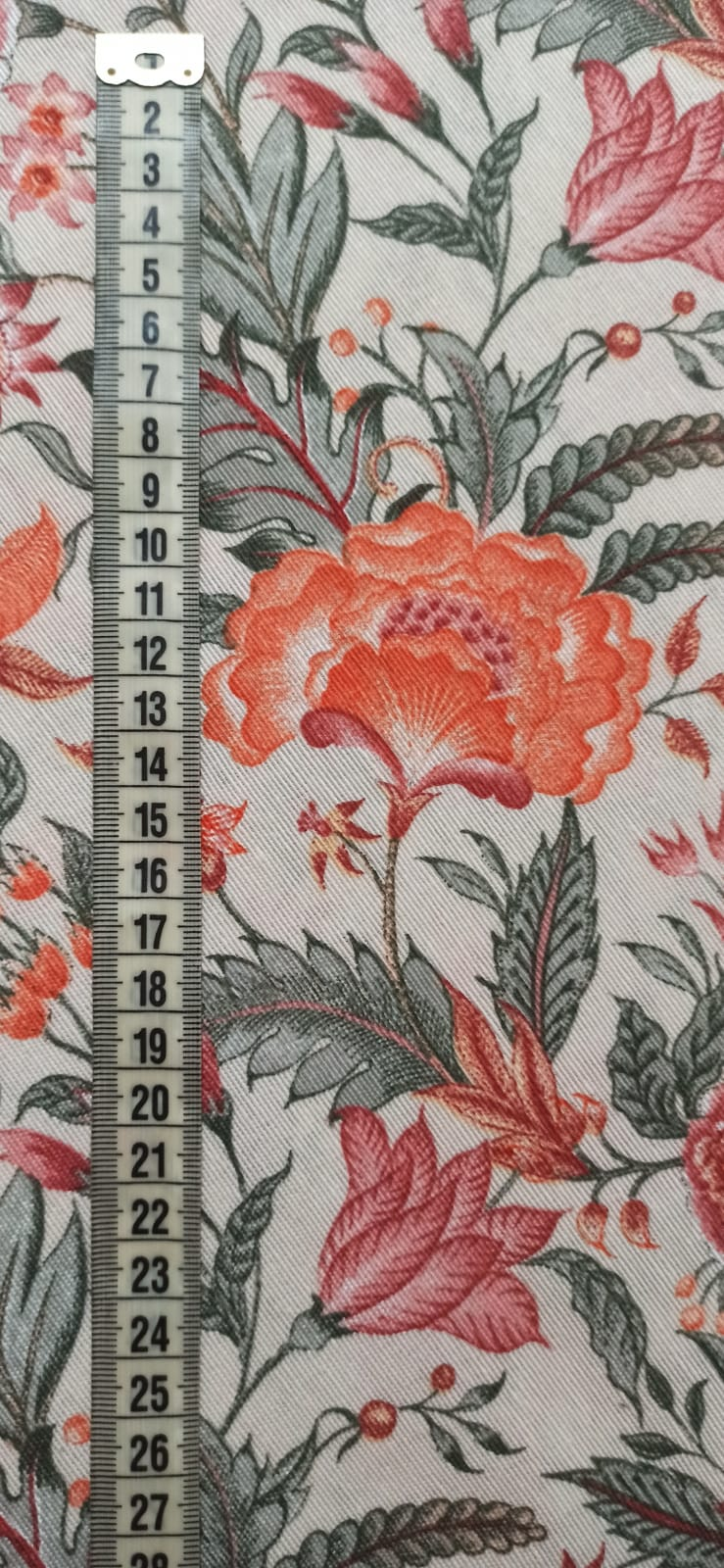 Cinta métrica sobre la loneta floral naranja mostrando el tamaño del estampado