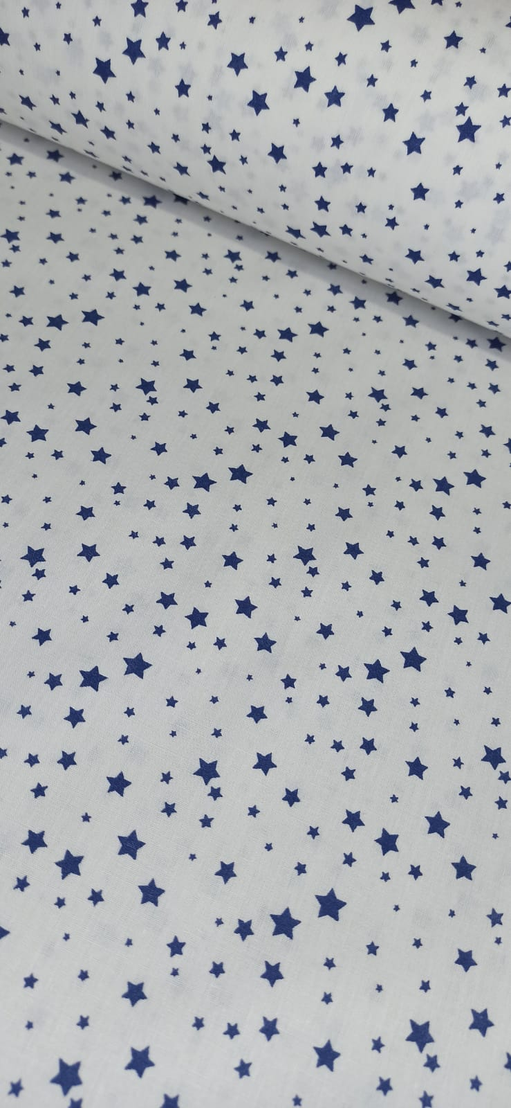 Tela de algodón blanco con estrellas azul marino de distintos tamaños, vista extendida